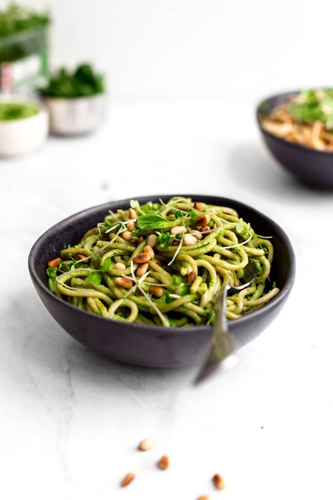 Creamy green pasta in a black bowl.