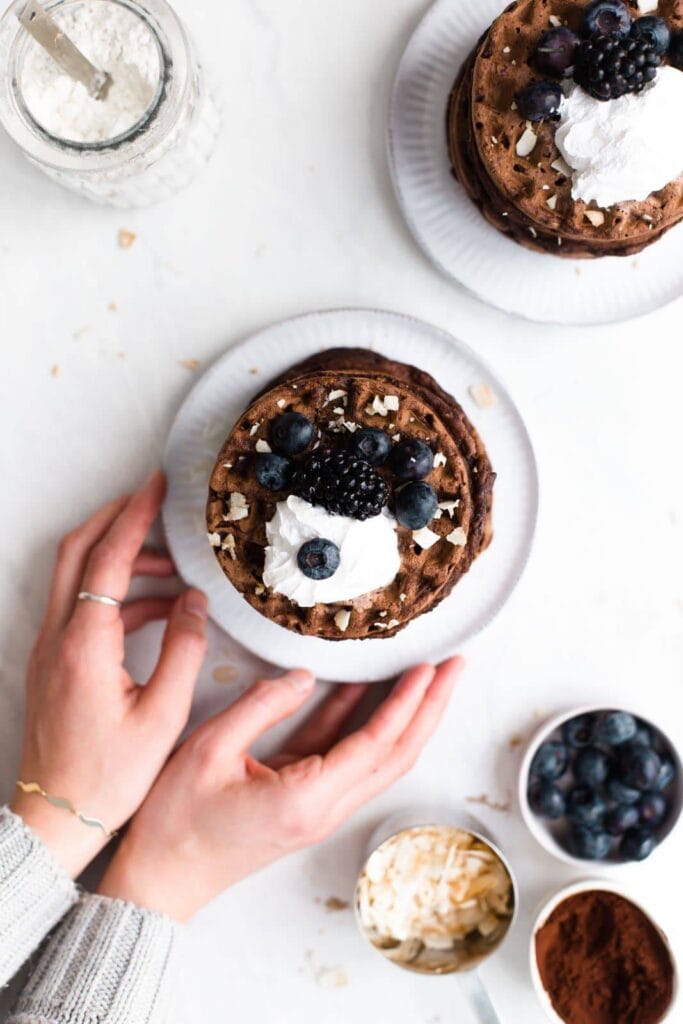 Hands reaching for waffles on a small plate