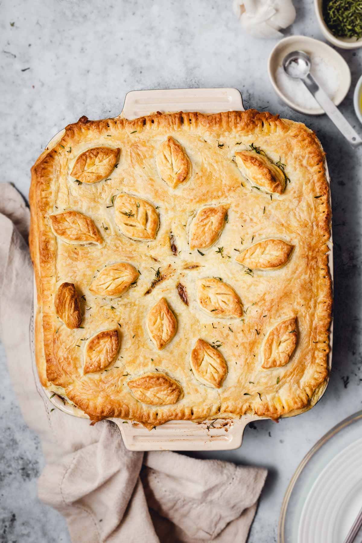 A baked vegan pot pie on a grey background. 