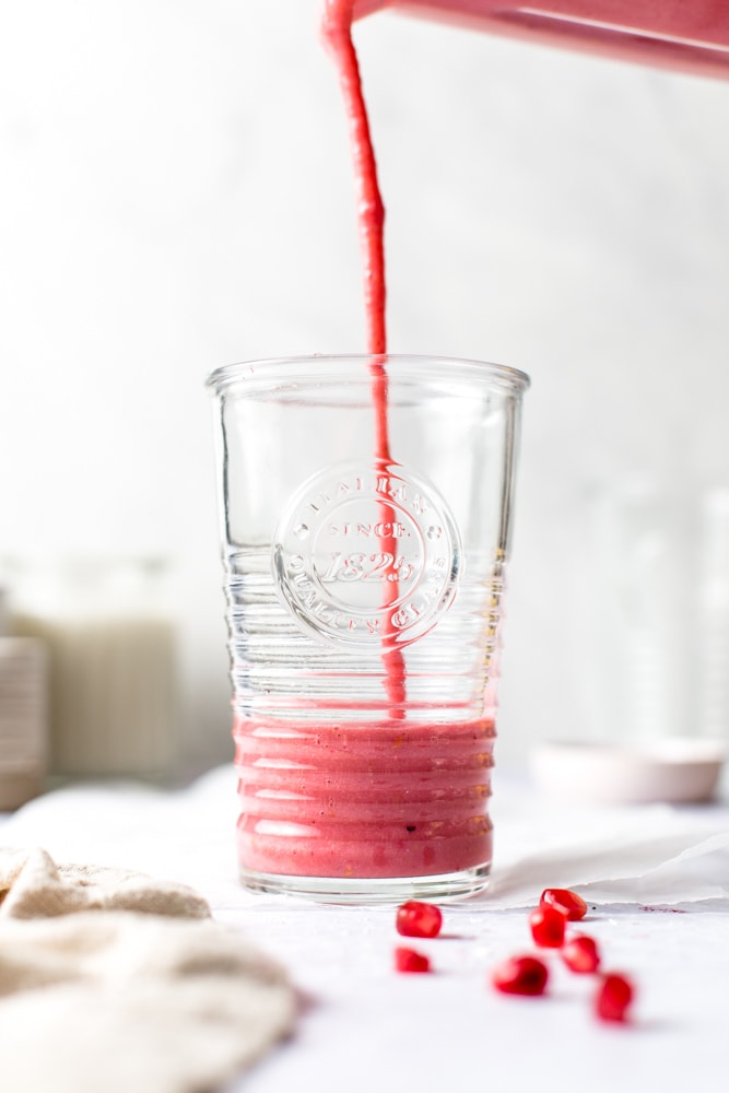 Pomegranate smoothie being poured into a glass. 