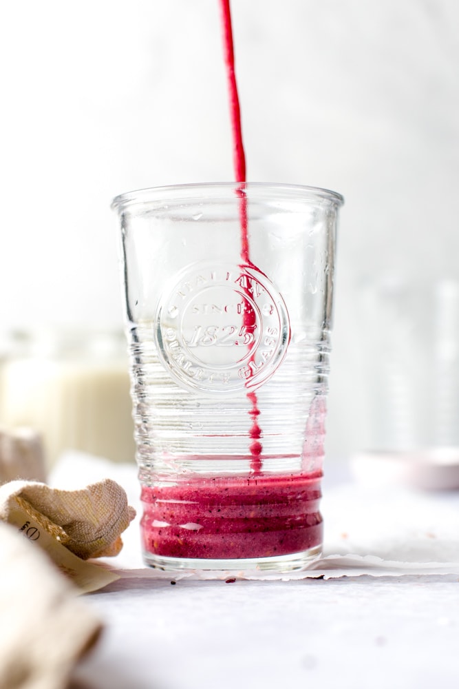 Mixed fruit smoothie being poured into a glass. 