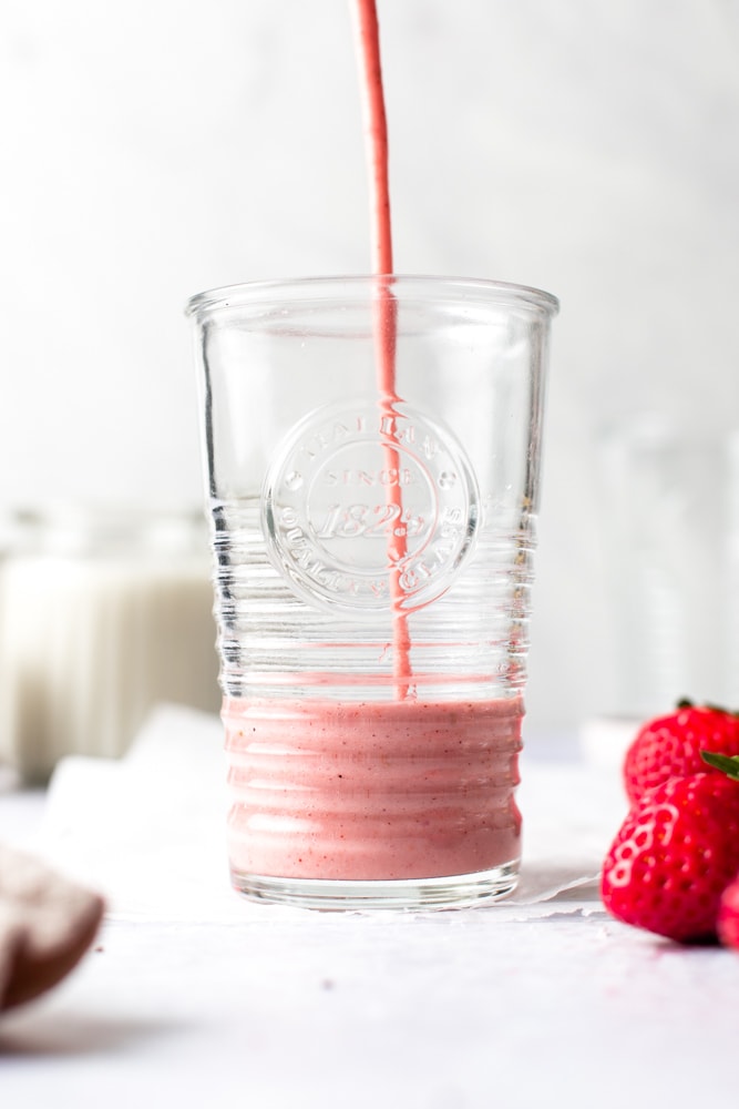 Pink smoothie being poured into a glass. 