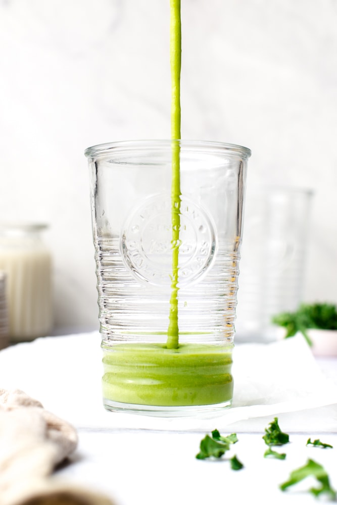 A green smoothie being poured into a glass. 