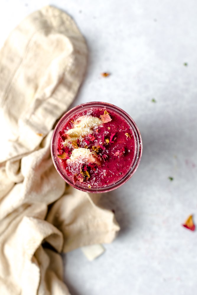 An overhead close-up view of red smoothie in a glass. 