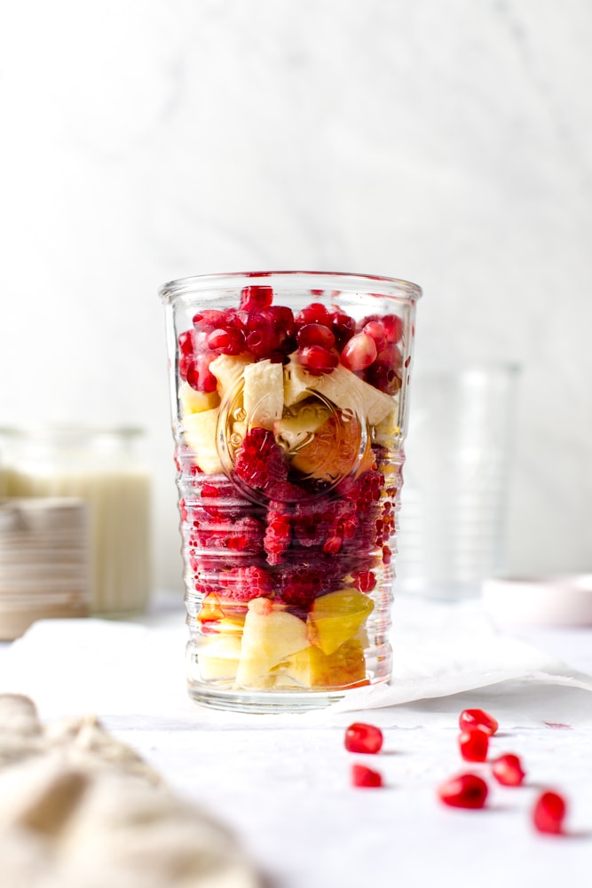 A glass containing all the fruit needed to make pomegranate smoothie. 