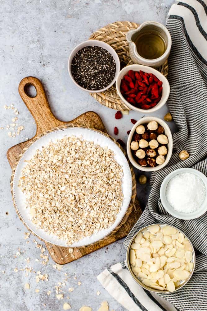 Oats, chia seeds, goji berries, hazelnuts, almonds laid out on a flat surface. 