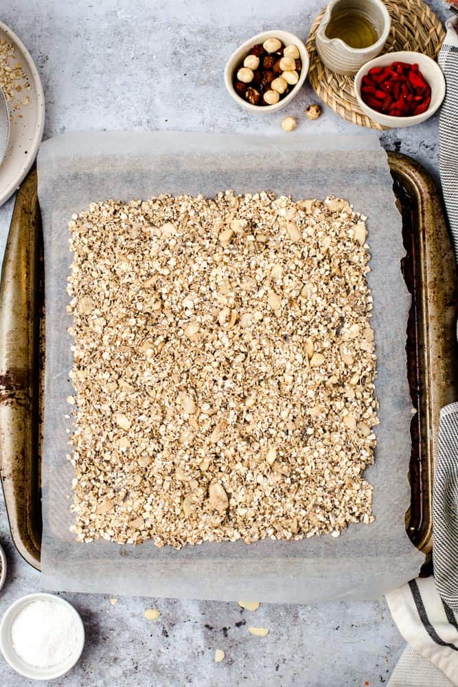 Lined baking tray full of vegan granola before baking. 