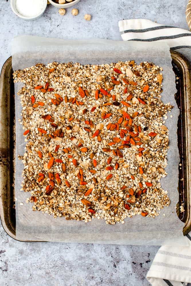 Lined baking tray featuring baked granola with goji berries. 