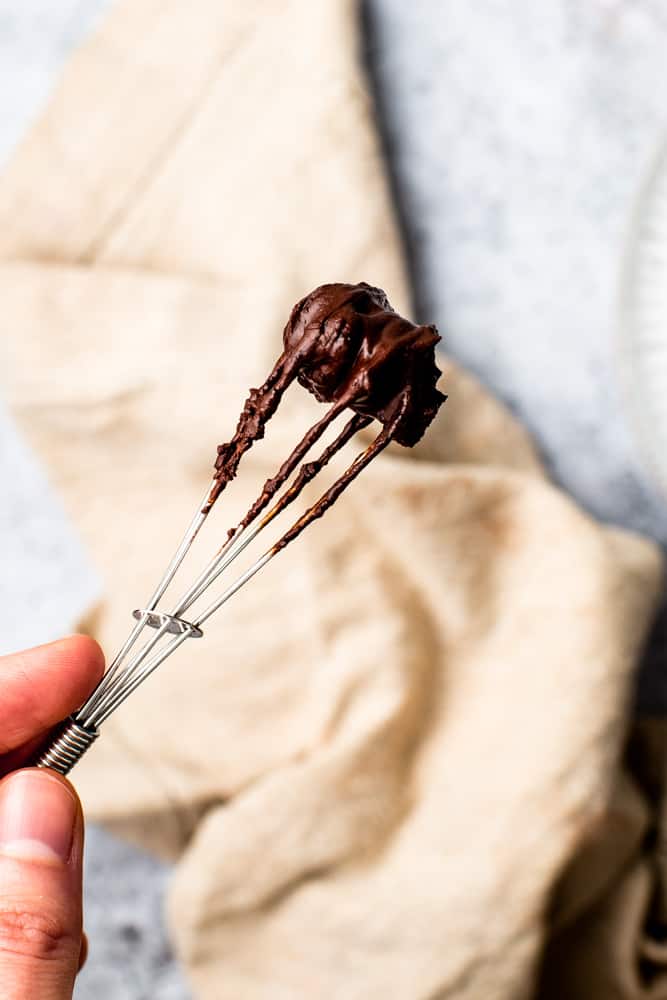 A metal whisk coated in dairy free hot chocolate paste. 