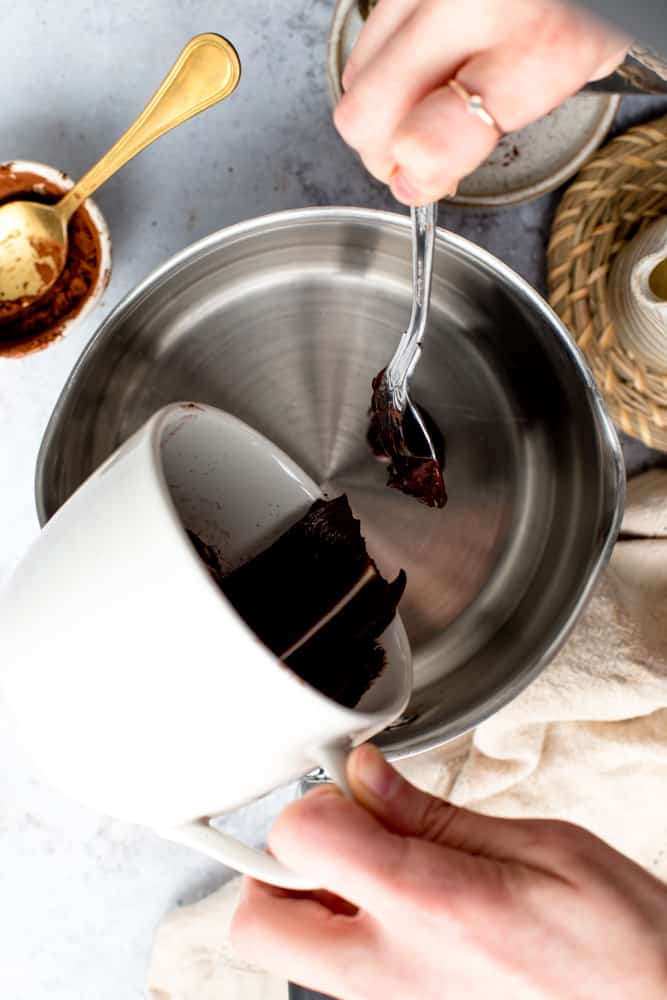 Dairy free hot cocoa paste being transferred from a mug to a small pan.