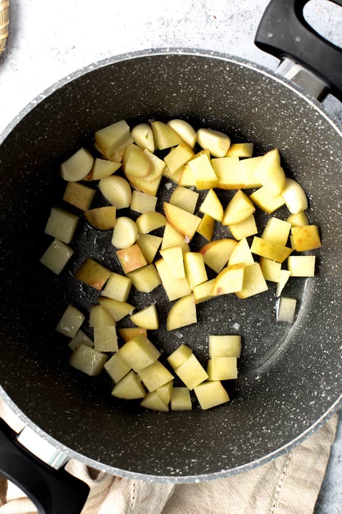 Small potato cubes and garlic on a marble pan. 