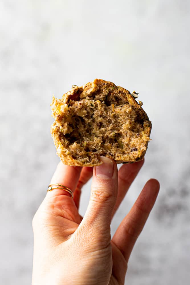 A hand holding a savoury vegan muffin with a bite taken out. 