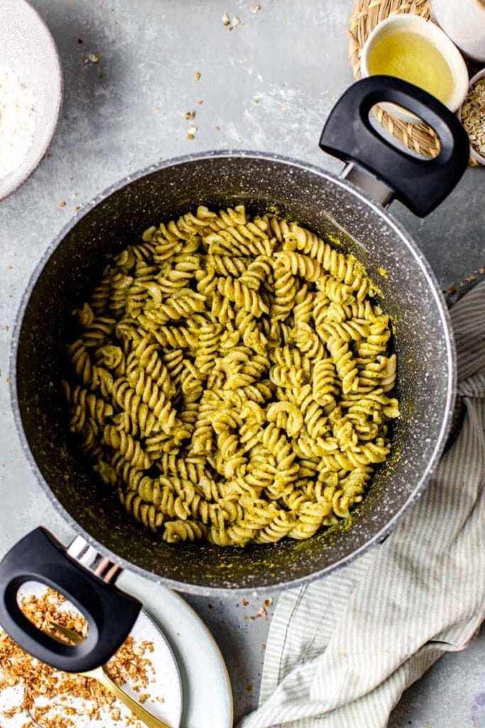 A large marble cooking pan full of pesto pasta. 