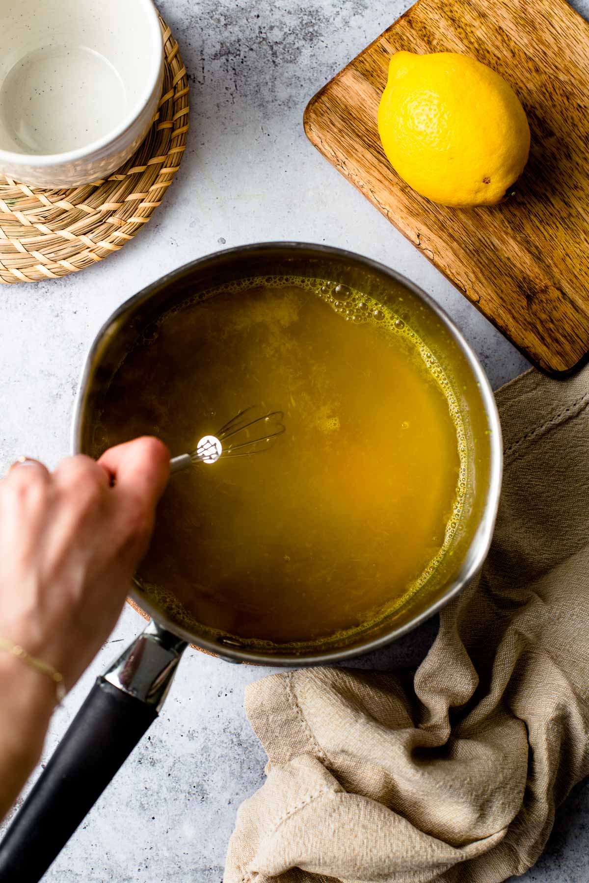 A hand stirring a small pan of cinnamon ginger tea. 