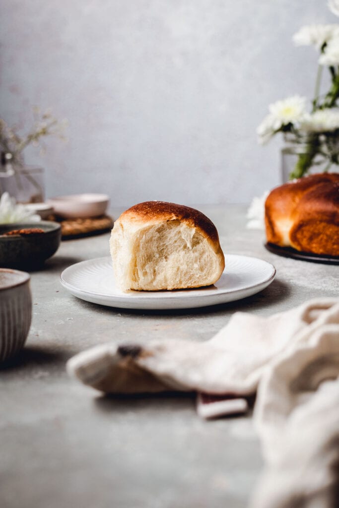 A single dinner roll placed on a small round plat. 