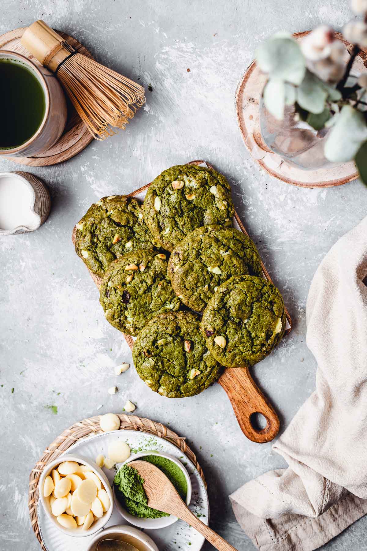 Six cookies placed on a small wooden choppping board and surrounded by various props. 