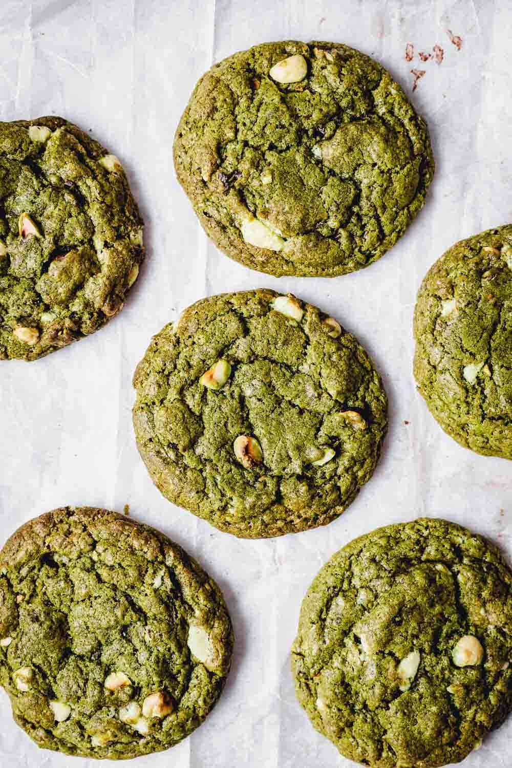 Six cookies placed on a parchment paper shown from the top.