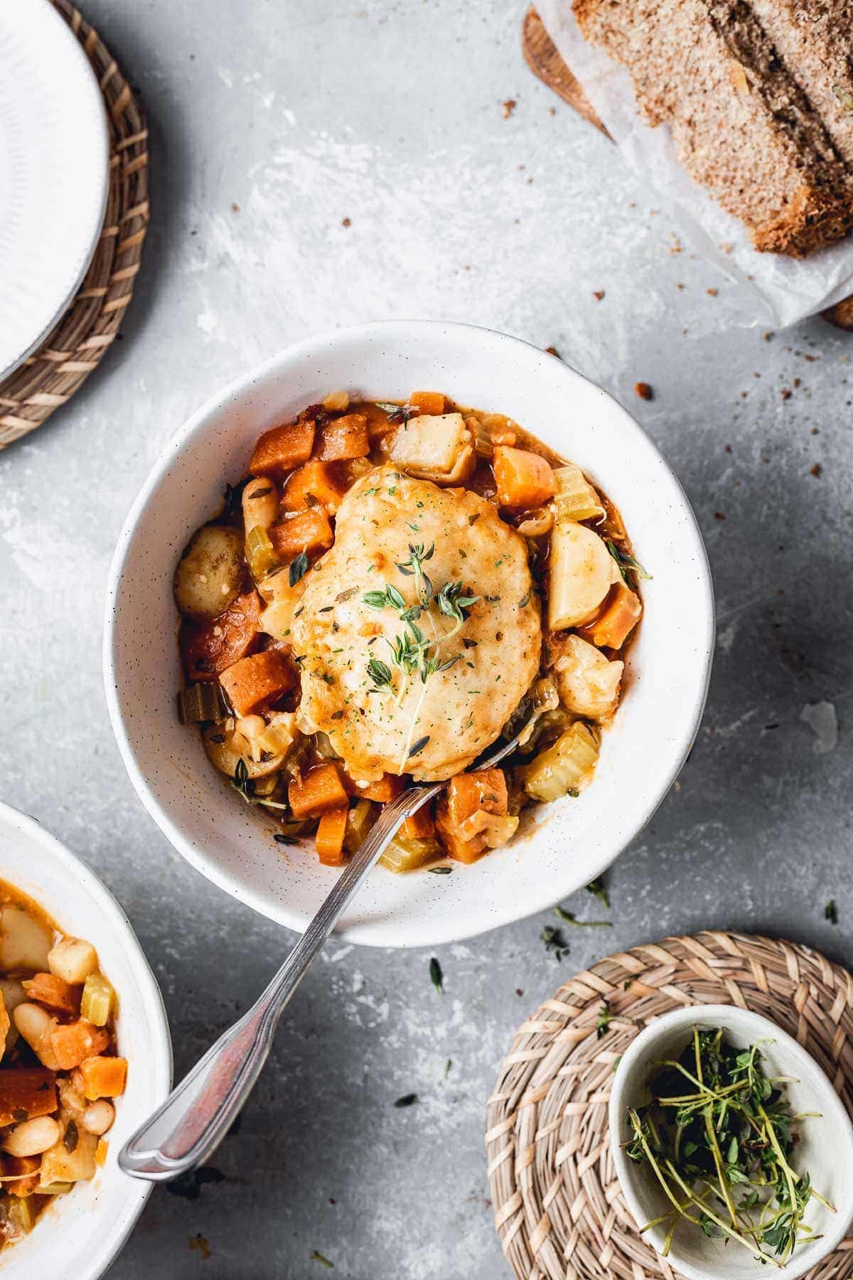 Vegetable stew and a dumpling in a white bowl. 