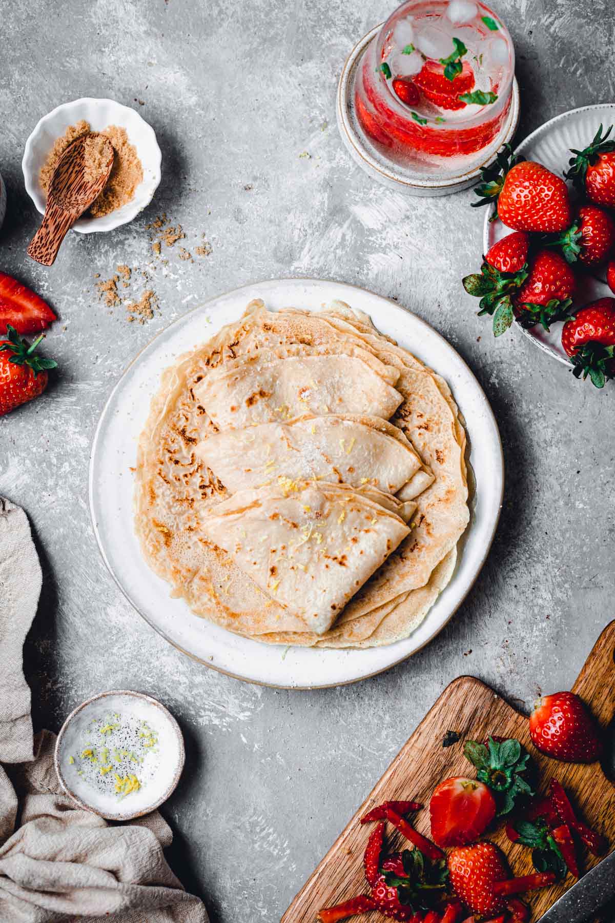 Several vegan crepes folded into a triangle and placed on a round plate.