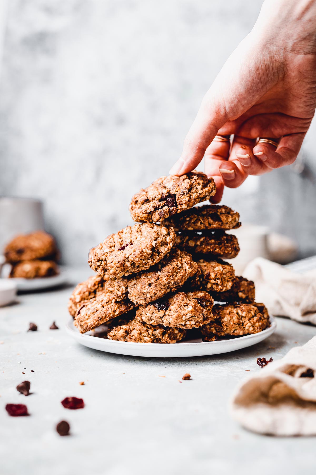 A hand reaching out for a stack of vegan oatmeal cookies. 