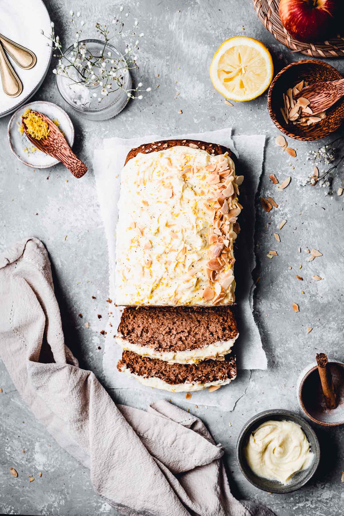 An overhead view of apple sauce cake on a flat background with two slices laying flat. 