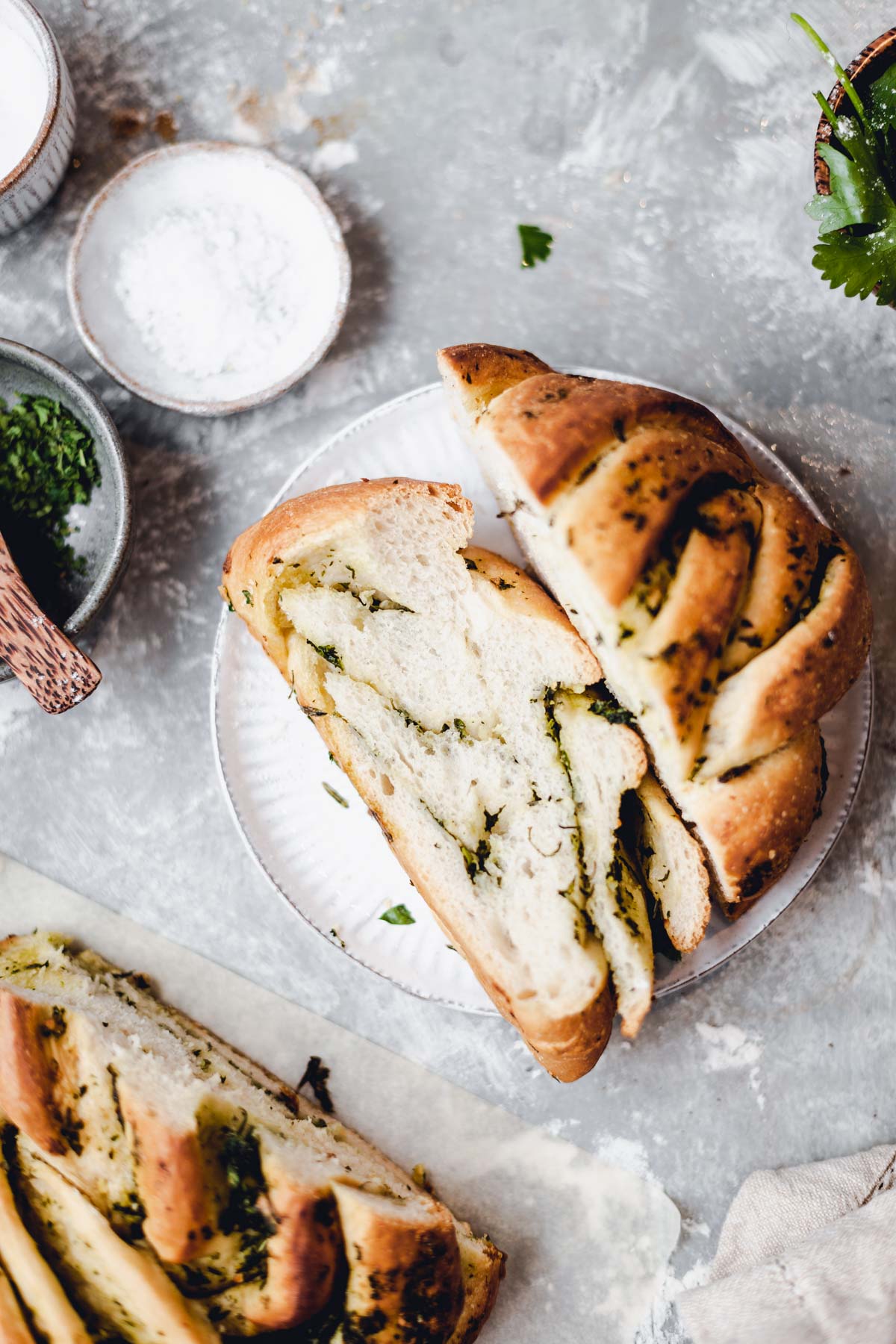 A slice of garlic twisted bread with herbs on a round plate.