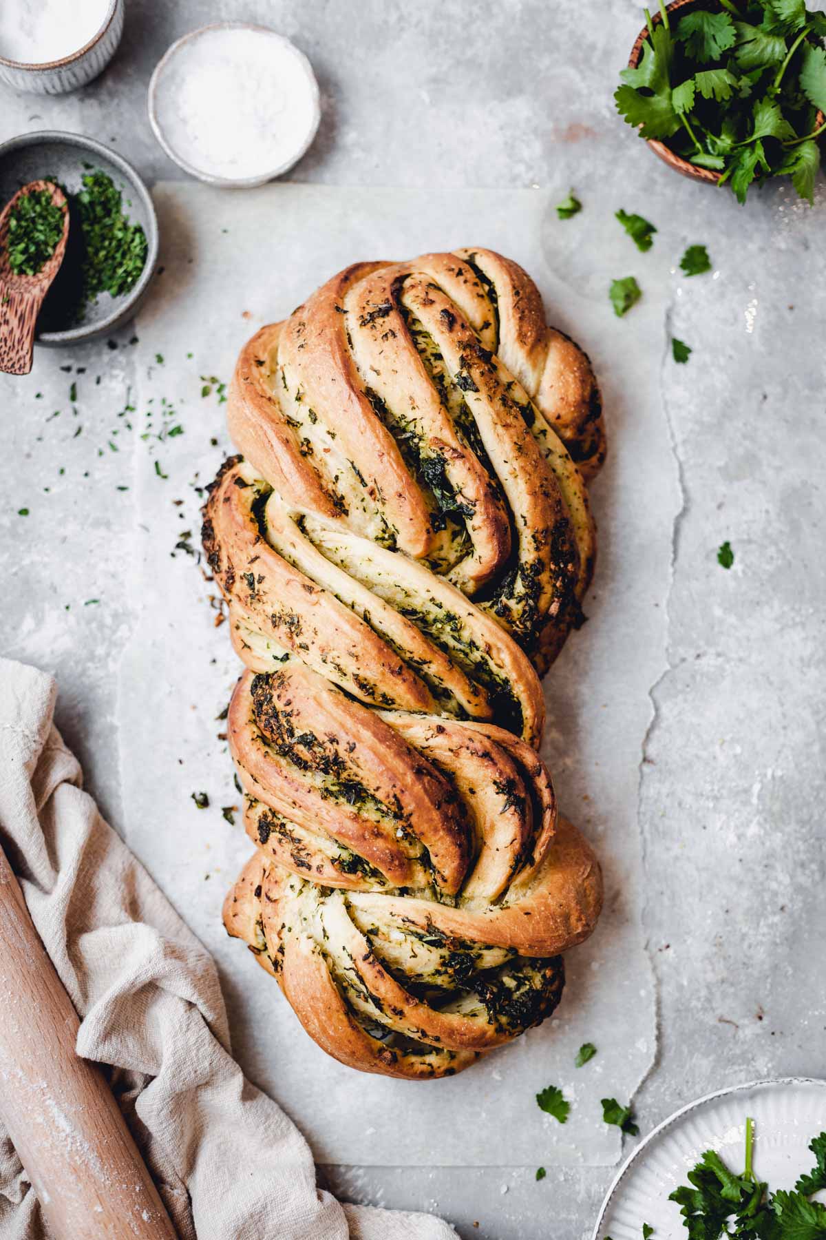 A load of herb bread laying flat on a baking paper.