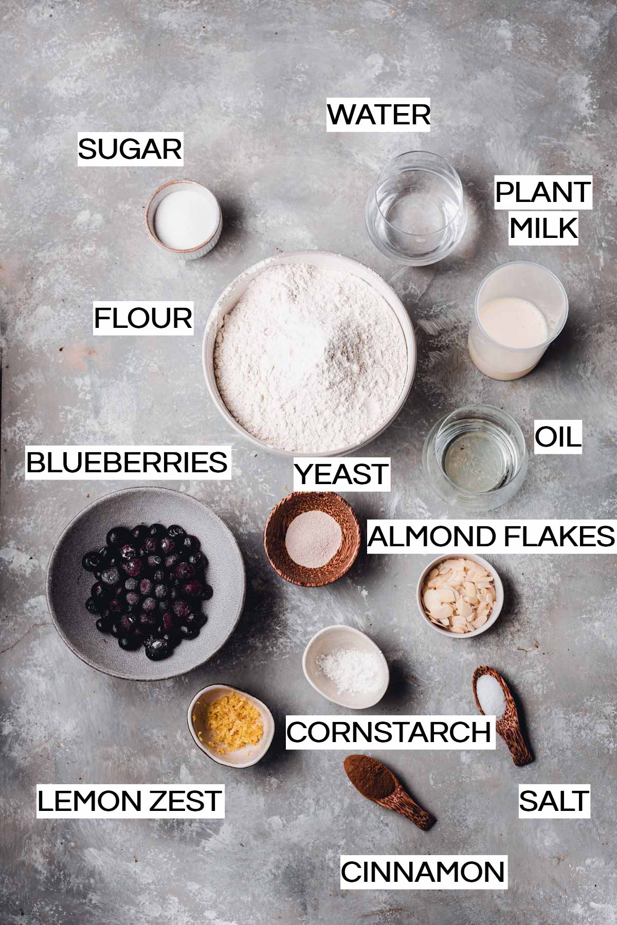 All the ingredients needed to make blueberry buns placed in cups and bowls. 