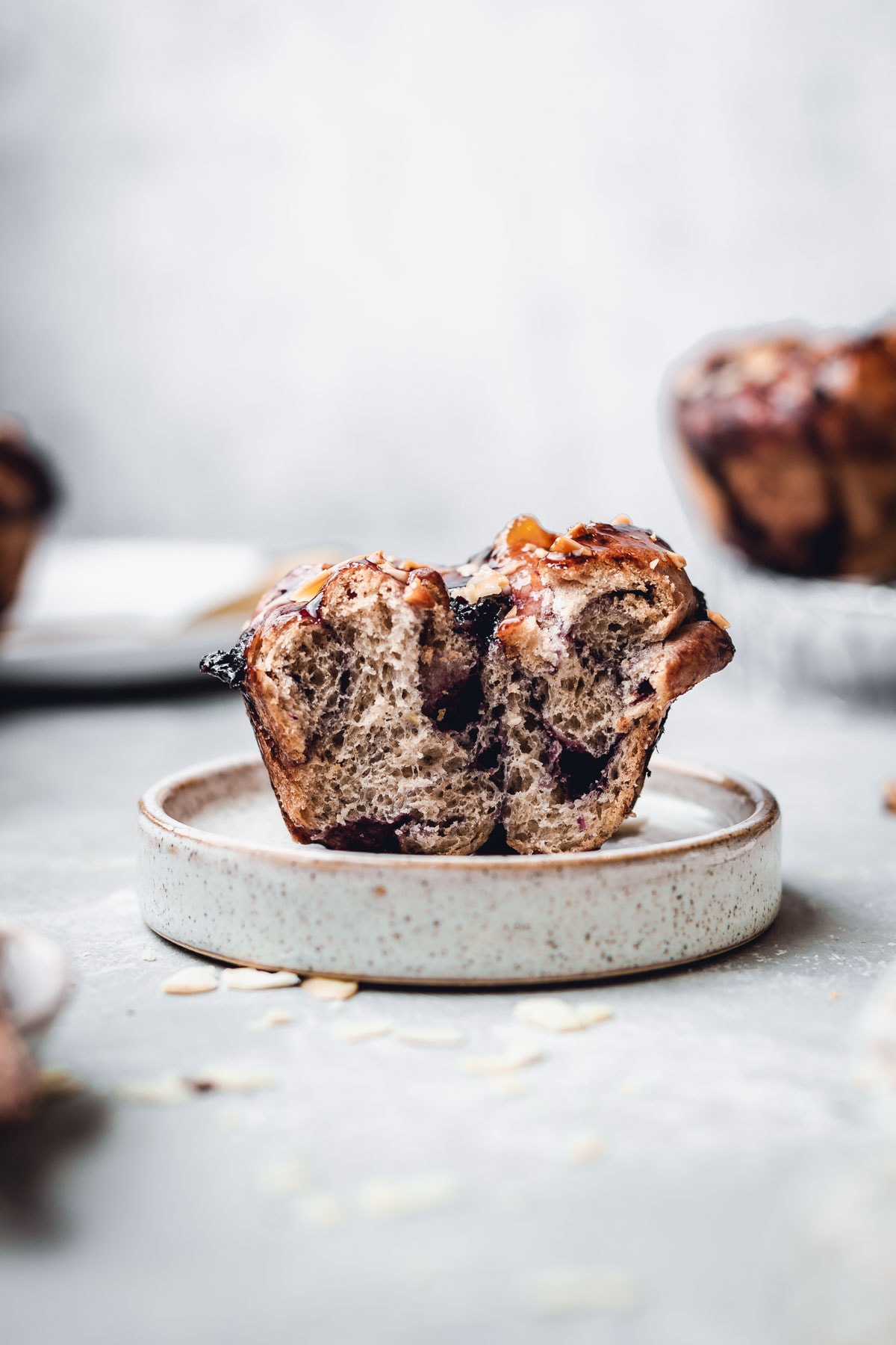 A side view of blueberry knot bun placed on a small round plate. 