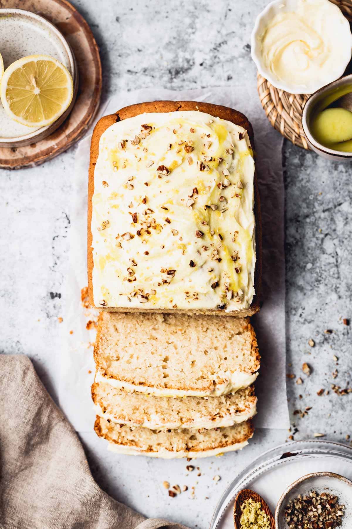 A lemon loaf cake placed on a flat surface with three slices cut out. 