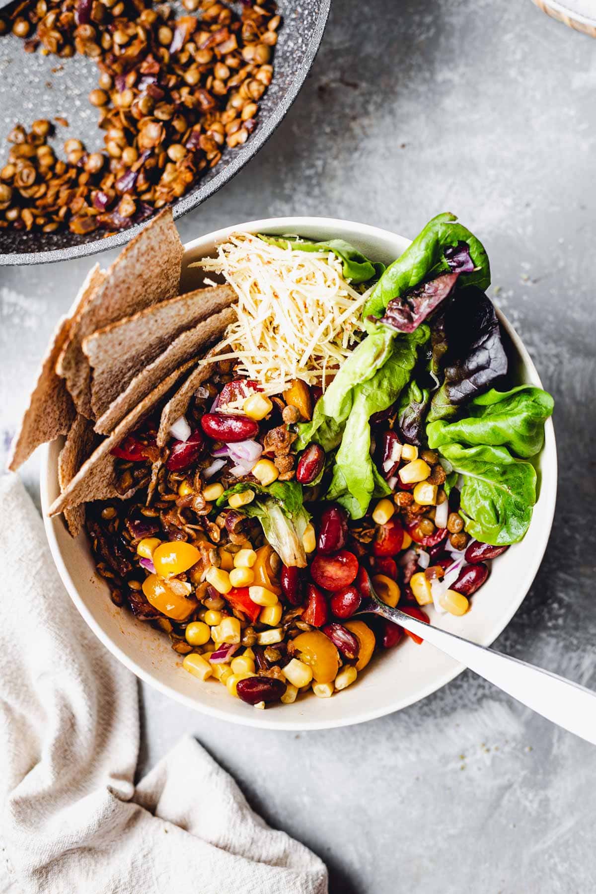 A bowl of mixed taco salad with a fork inserted in the middle. 