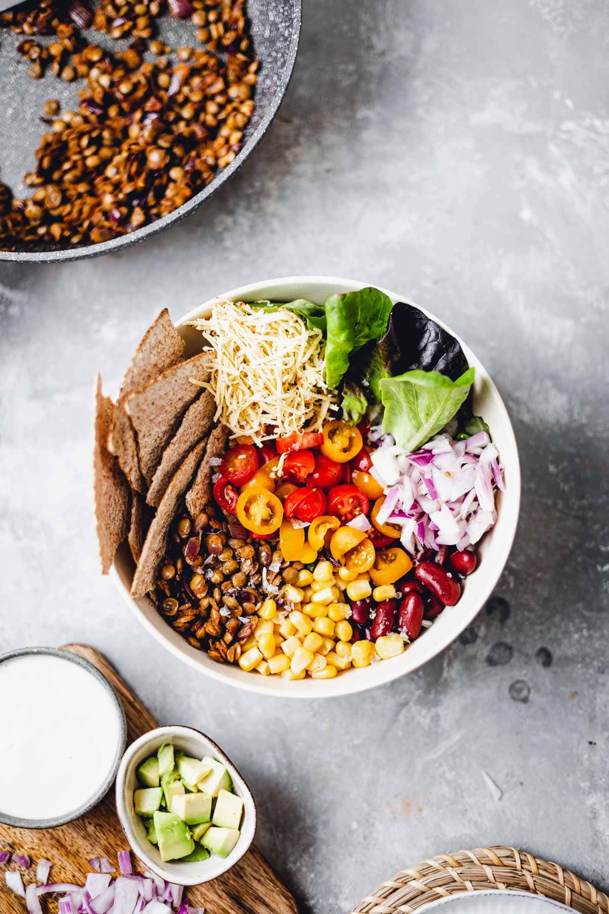 A bowl filled with colourful vegetables and crispy tortilla pieces. 