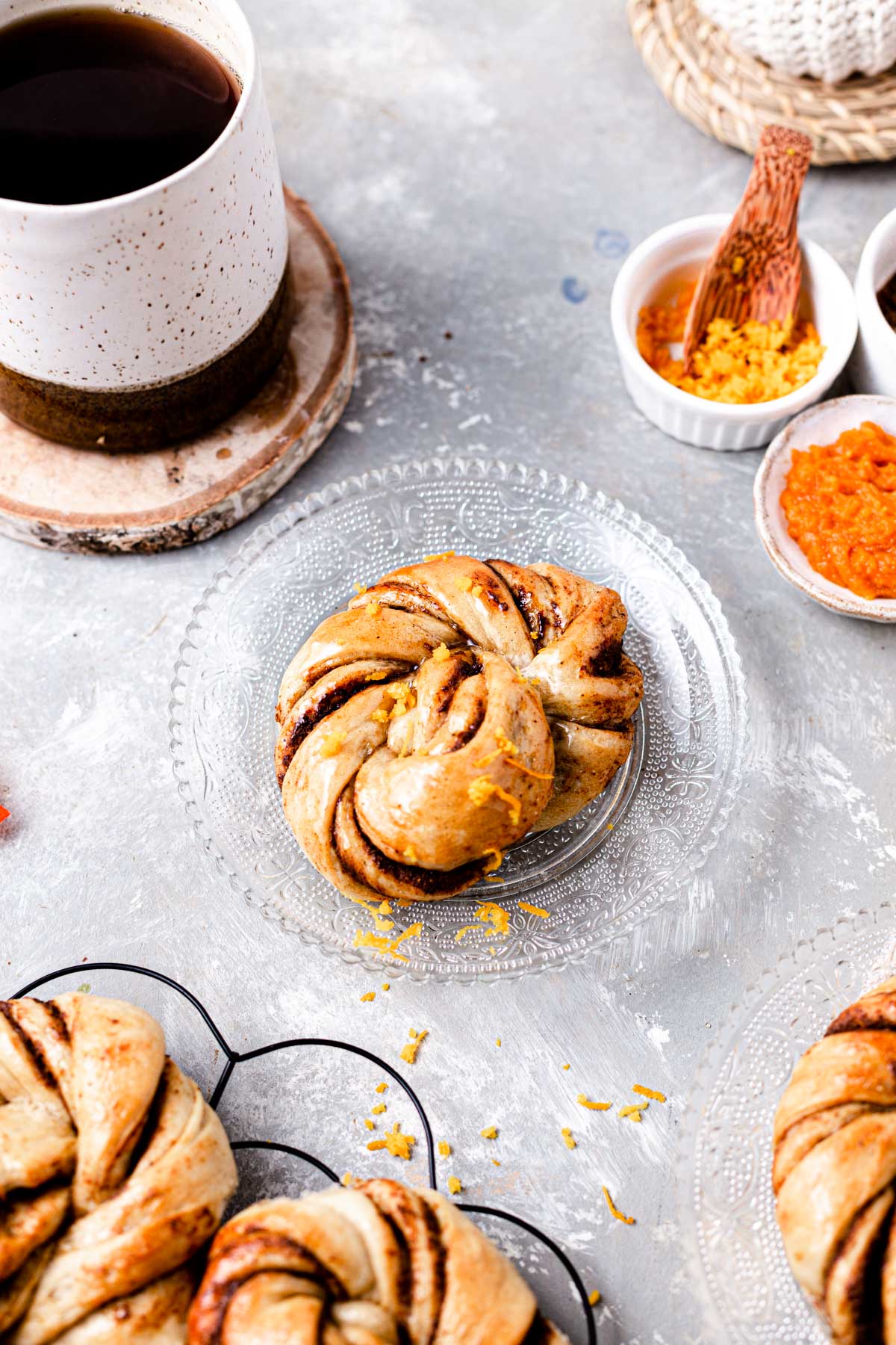 A single glazed pumpkin bun placed on a glass plate. 