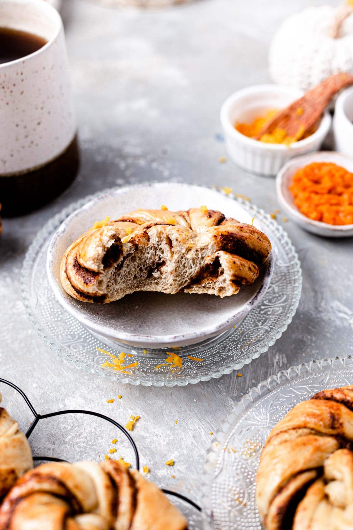 A pumpkin bun with a bite taken out of it placed on a plate.