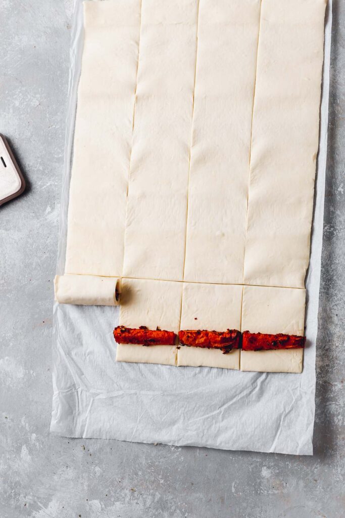 Rolled and sliced puff pastry with carrots placed on the pastry sheet. 