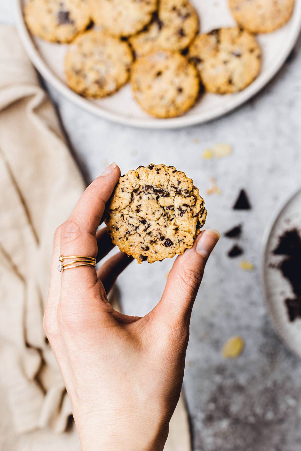 A hand holding a cookie with chocolate chips. 