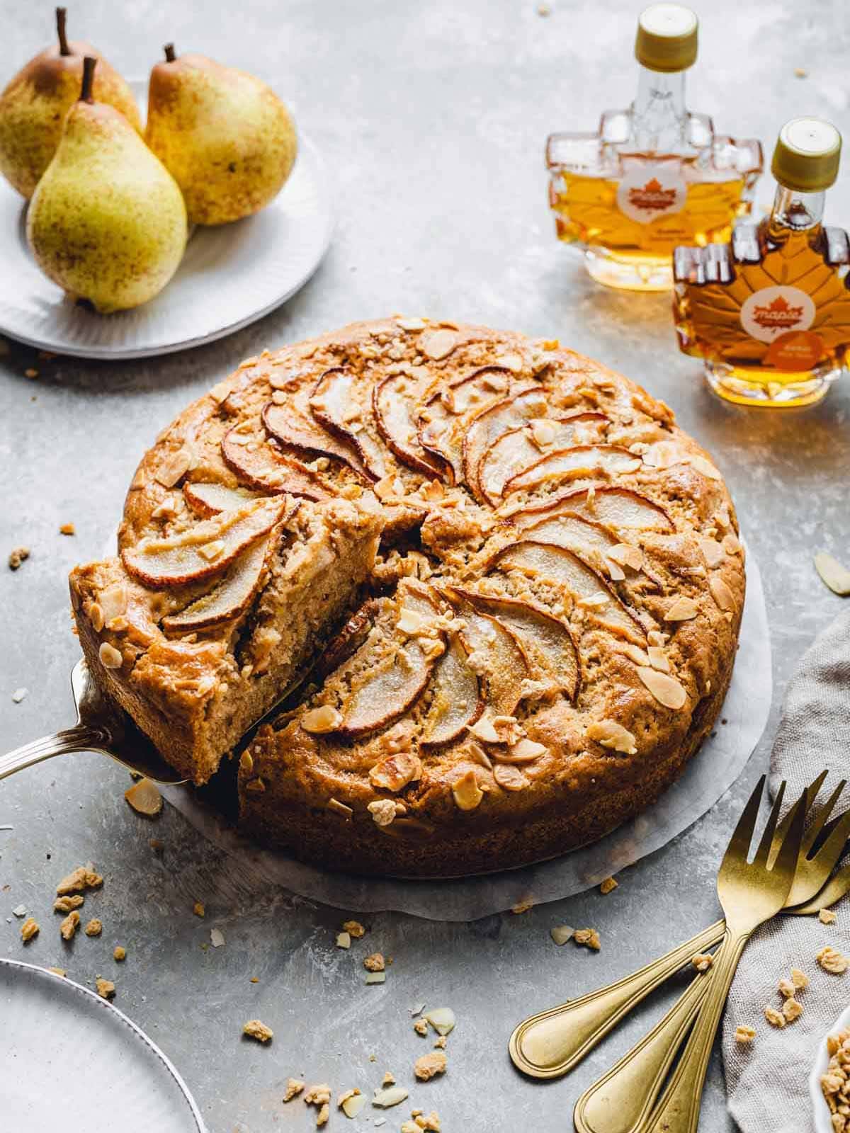 A side view of a pear cake with one slice being taken out.