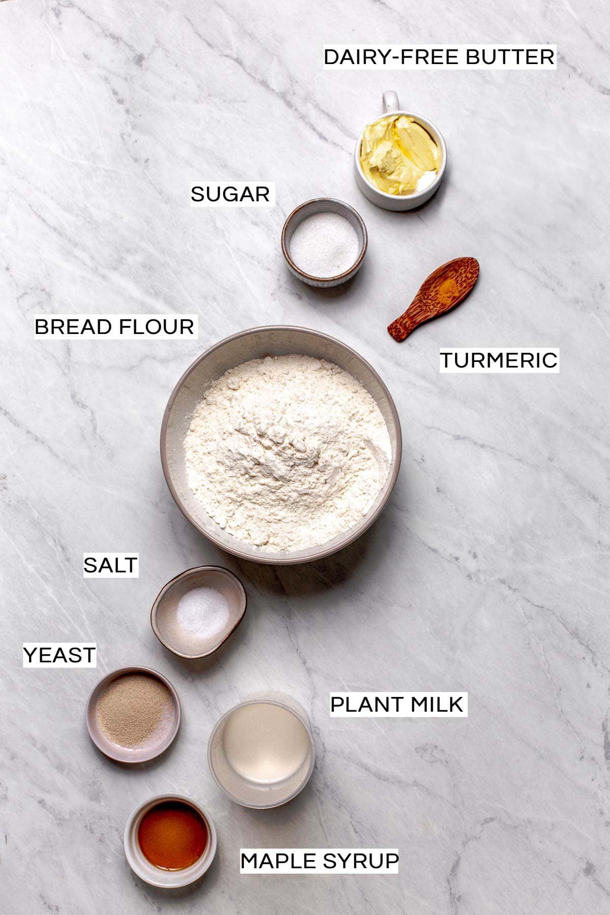 All ingredients needed to bake vegan hot dog buns laid out on a marble surface.