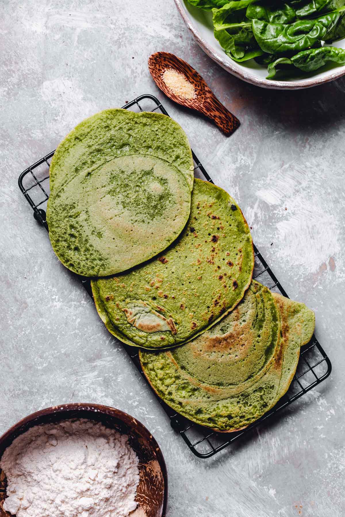 Three thin savoury crepes placed on a black cooling rack.