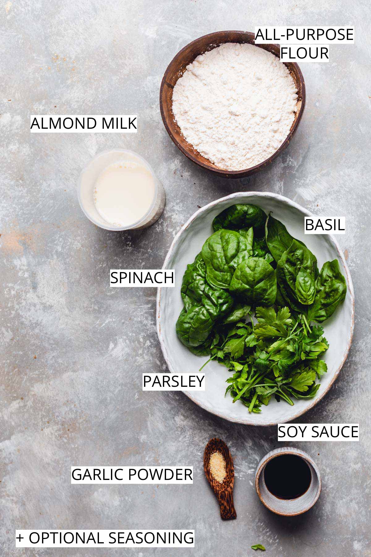 All the ingredients needed to make spinach crepes on a flat grey surface.