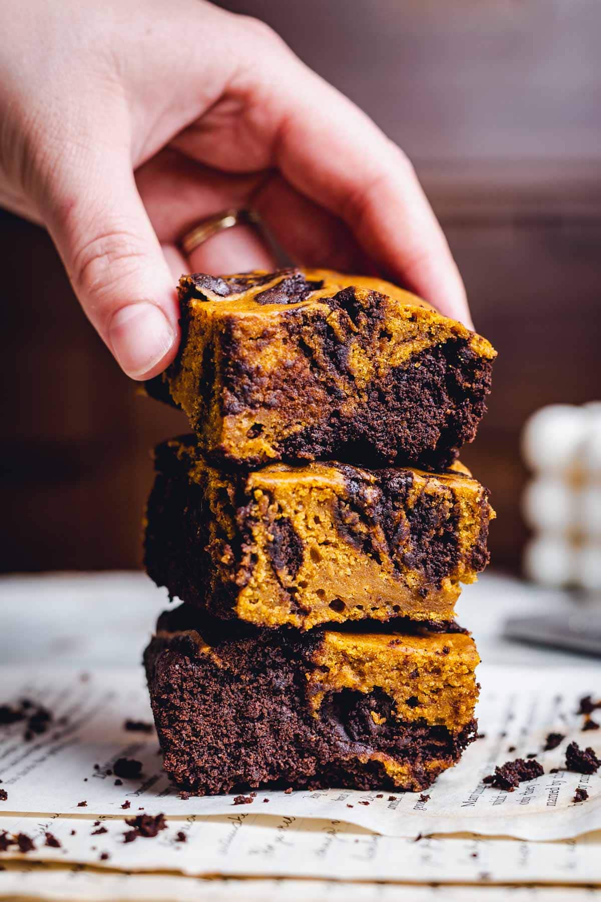 A stack of three brownies with a hand reaching out to grab the top one. 