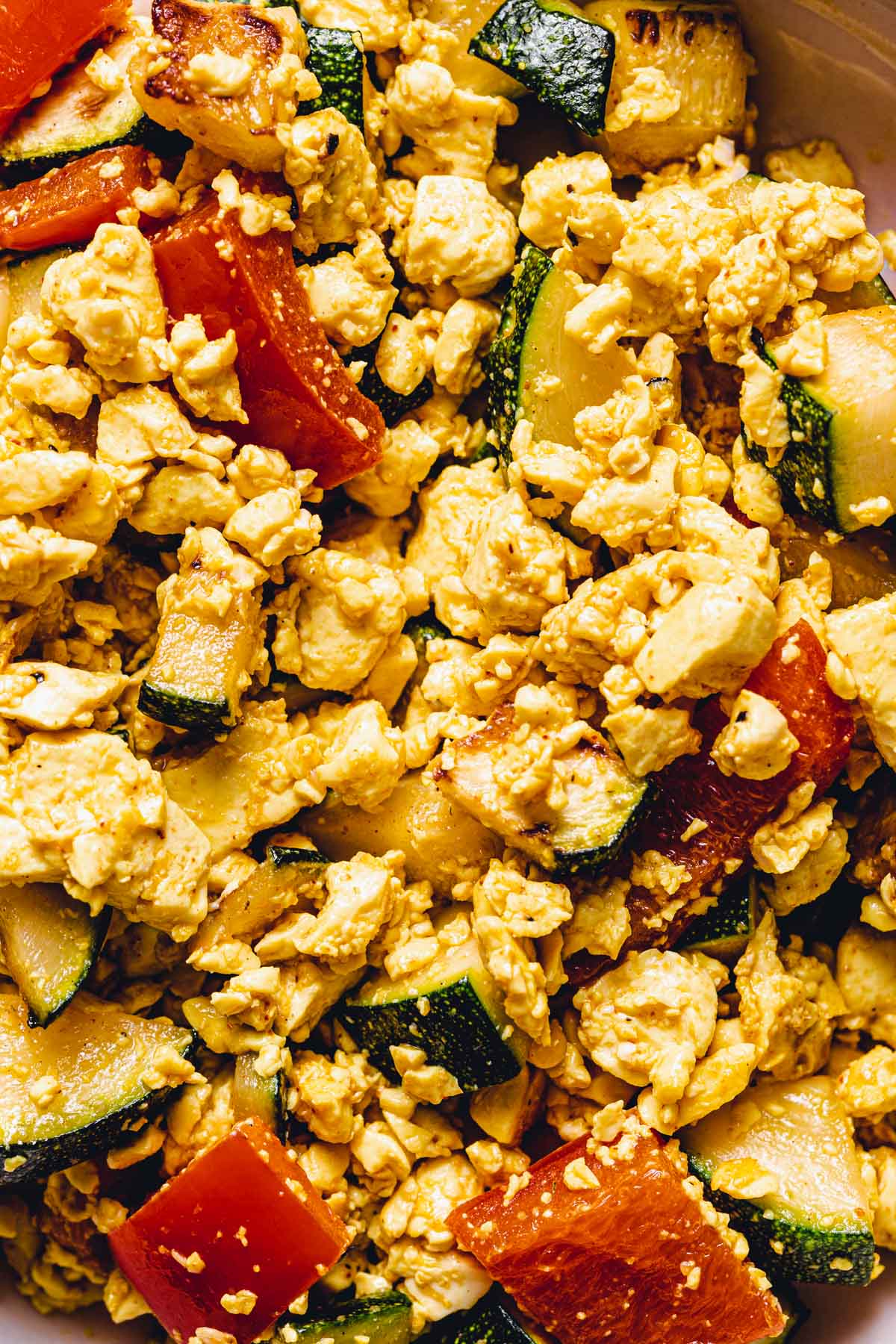 A close-up image of scrambled tofu with courgette and peppers. 