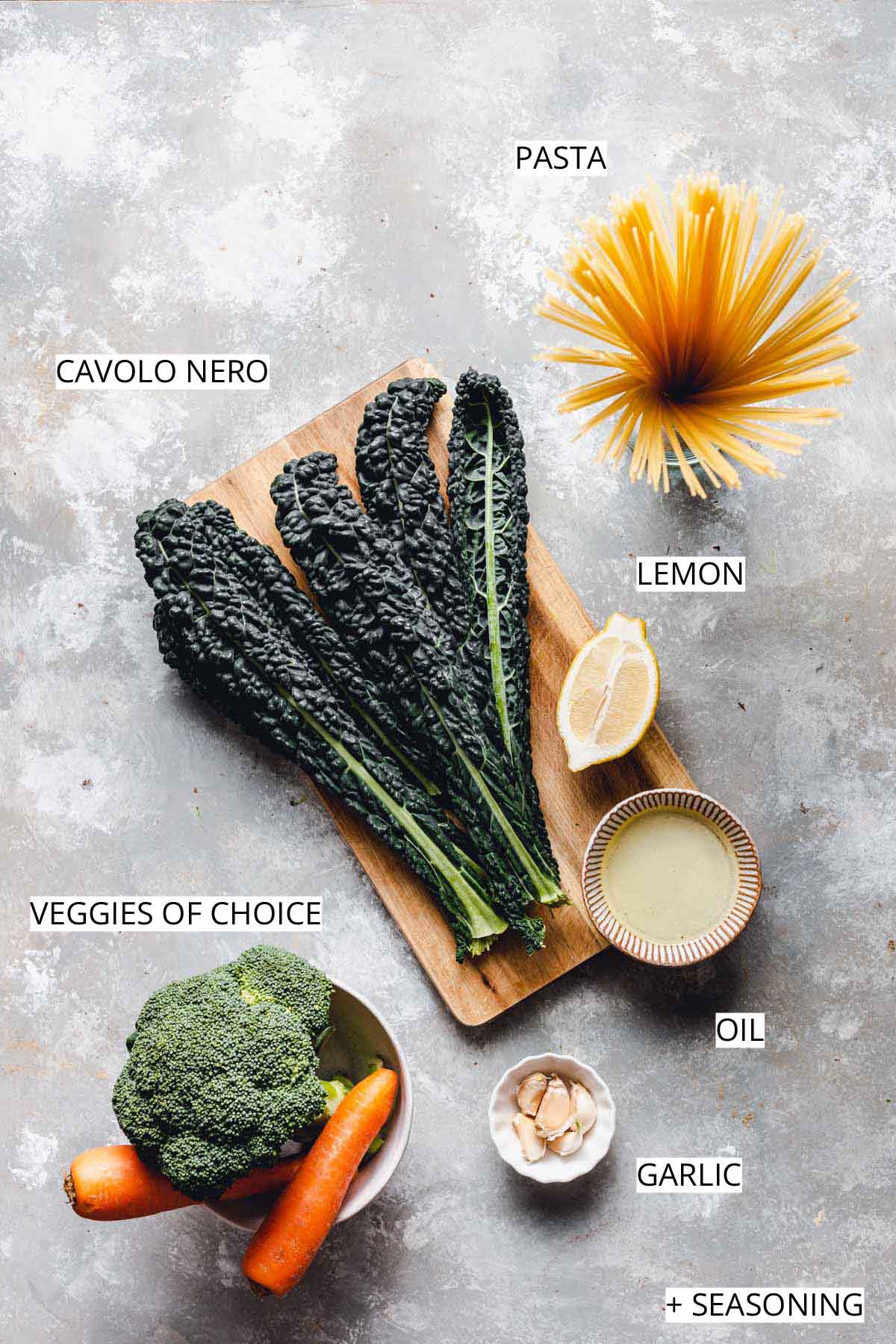 A flatlay image of all ingredients needed to make cavolo nero pasta on a grey surface.