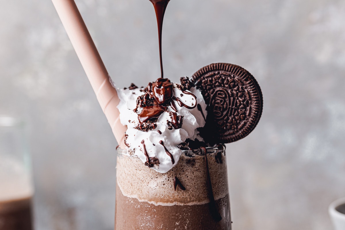 A close-up image showing an Oreo frappe with melted chocolate being poured on top.
