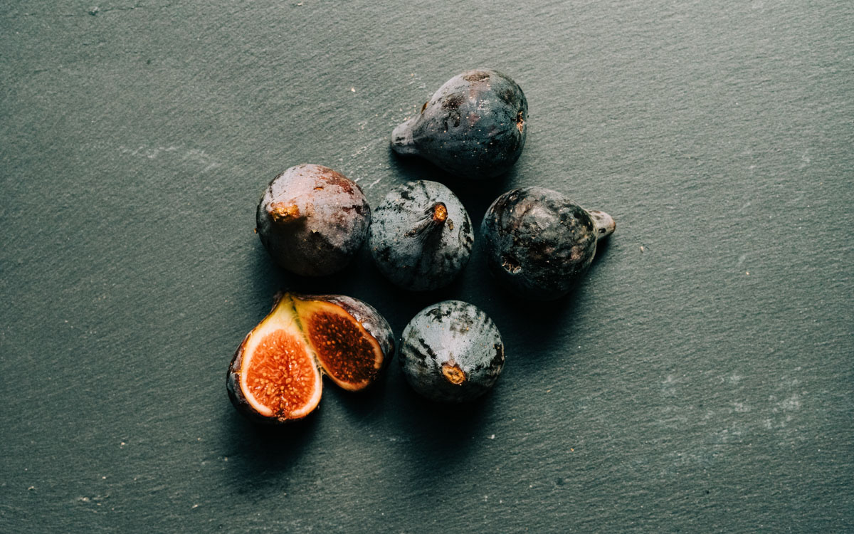 Various figs placed on a flat dark grey bacgkround.