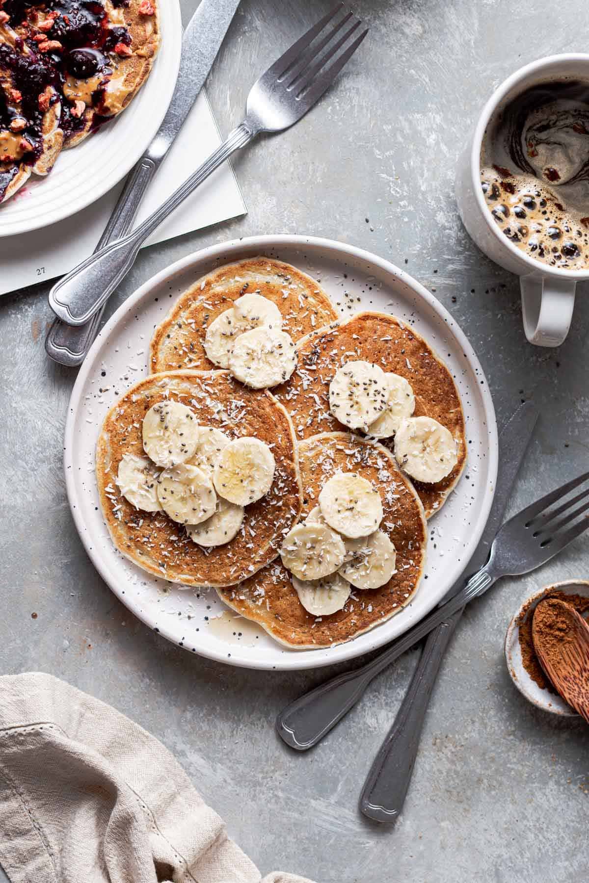 Four vegan pancakes on a plate topped off with banana.
