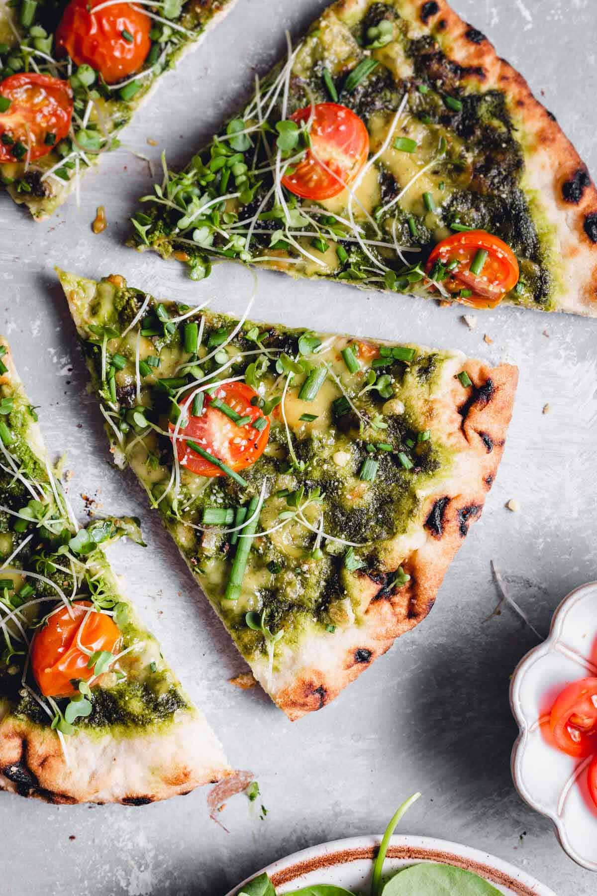 Slices of green pizza on a flat grey surface.