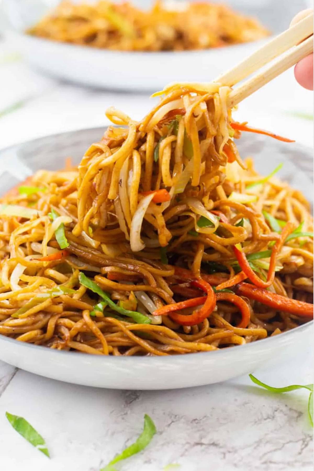 Chopsticks grabbing lazy vegan chow mein on a plate.