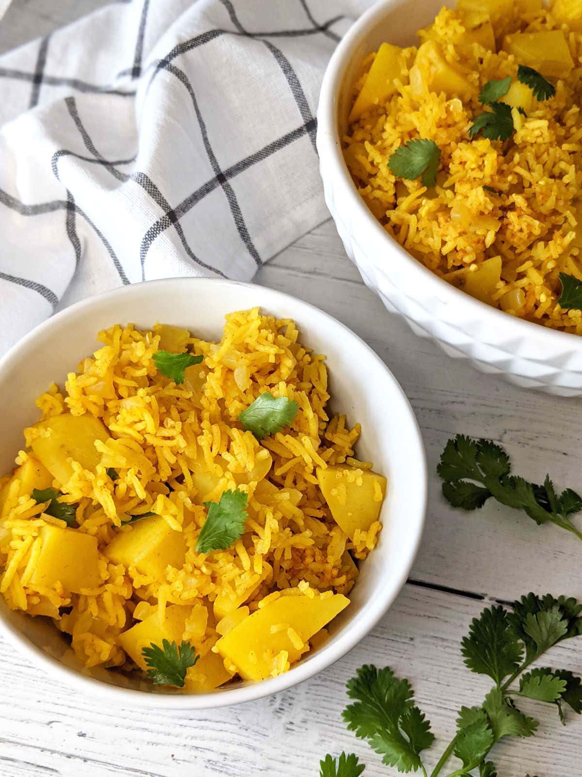 Two bowls of vegan potato rice on a wooden surface.