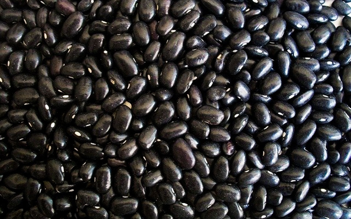 A close-up image of many black beans close to each other.